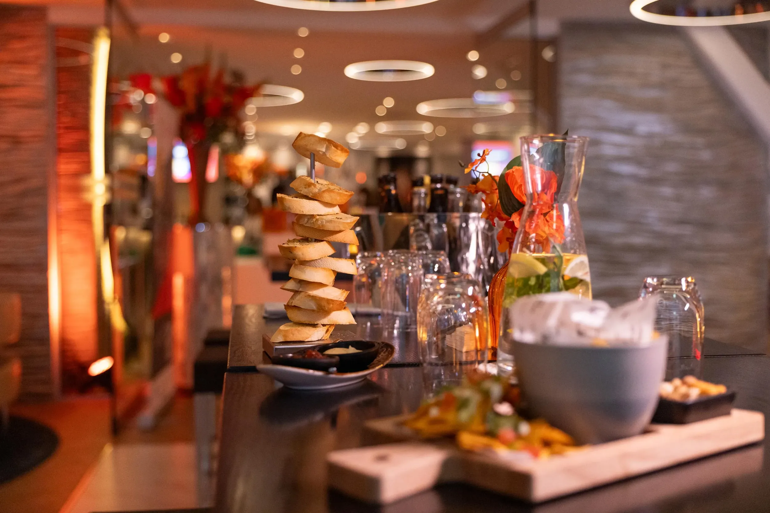 Verschillende snacks, een karaf met water en glazen staan klaar op de bar van de lounge van Green Village om gasten tijdens pauzemomenten van hapjes te voorzien.